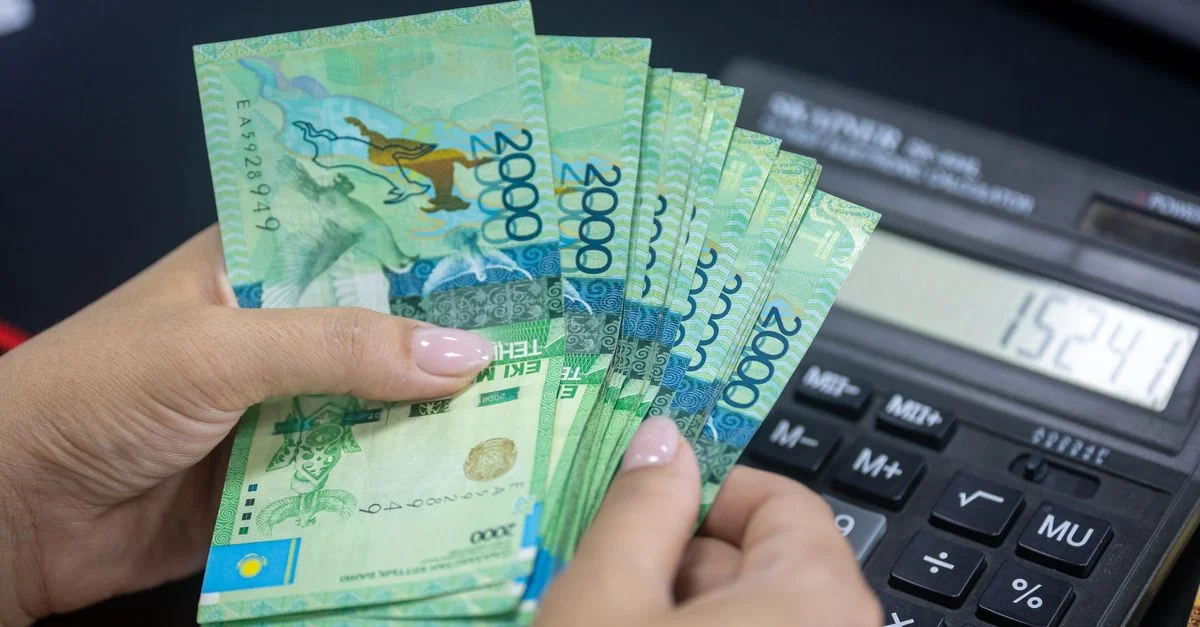 Personne comptant des billets de Tenge kazakhstanais à côté d'une calculatrice. Concept financier.