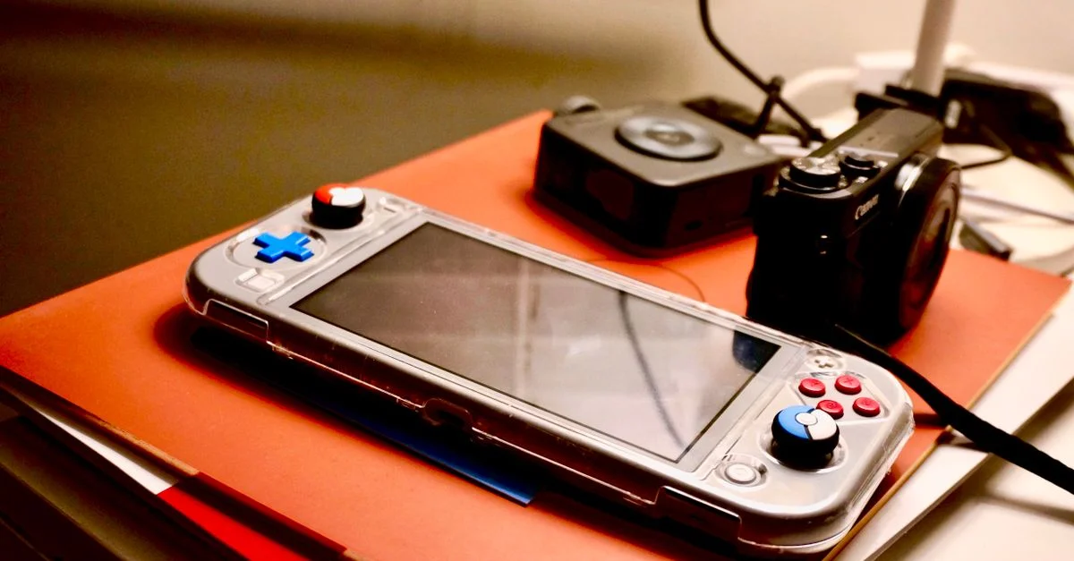 Une console de jeu portable à côté d'un appareil photo numérique met en valeur un setup moderne de divertissement et de technologie.